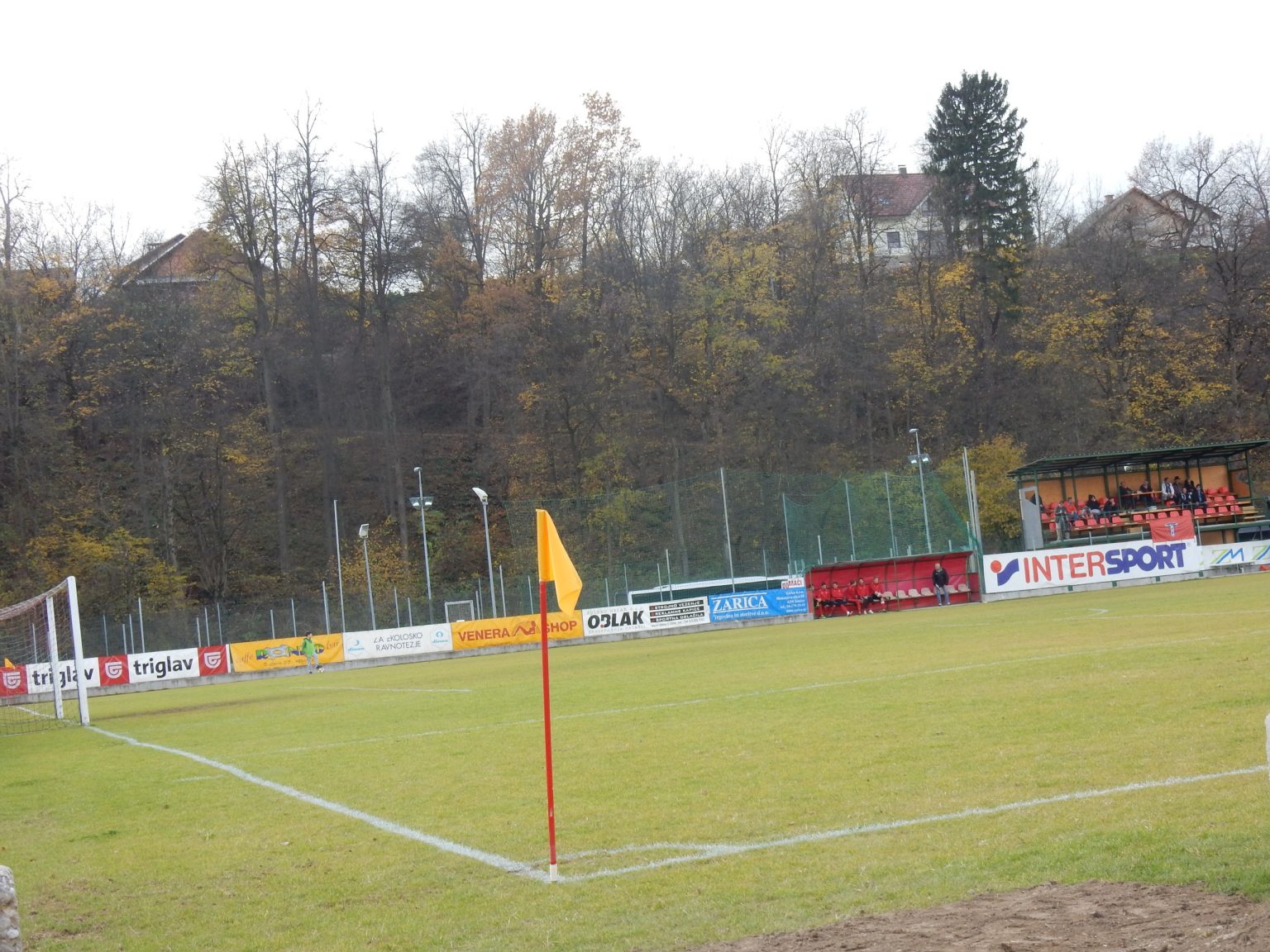 Kotni prapor ob glavnem igrišču, v ozadju pokrita tribuna in sponzorski panoji